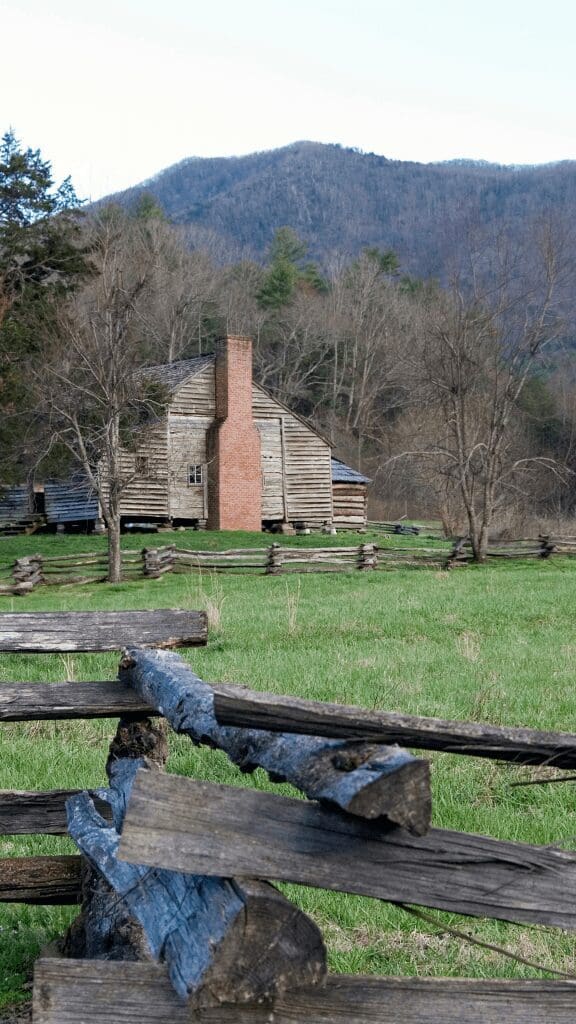 log cabin in distance with wooden rail fence in foreground