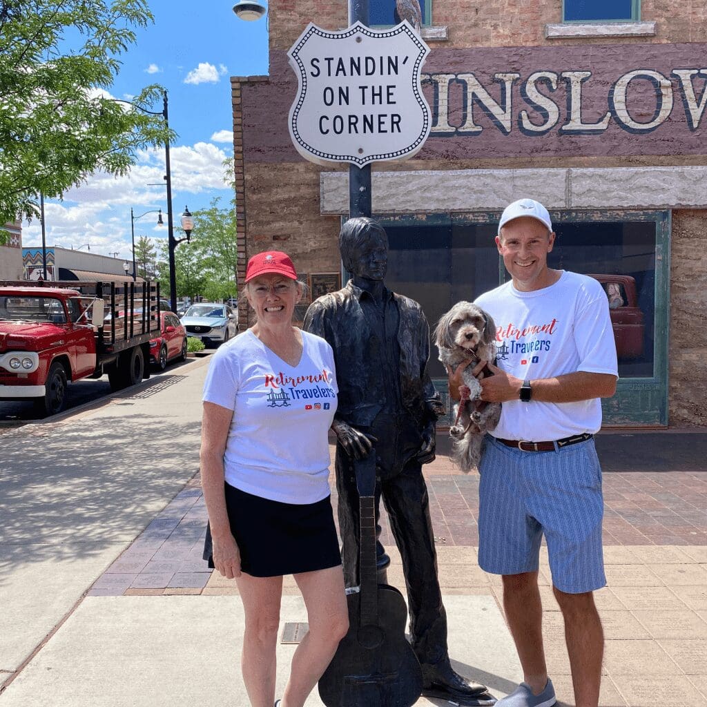 A man and woman holding their dog and standing by a statue