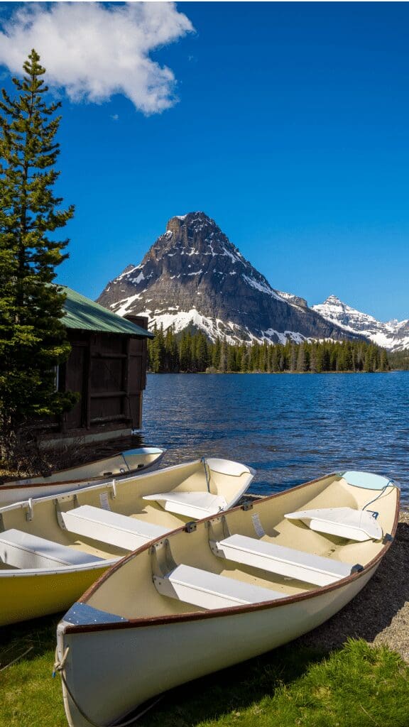 View of mountain next to lake with canoes in front