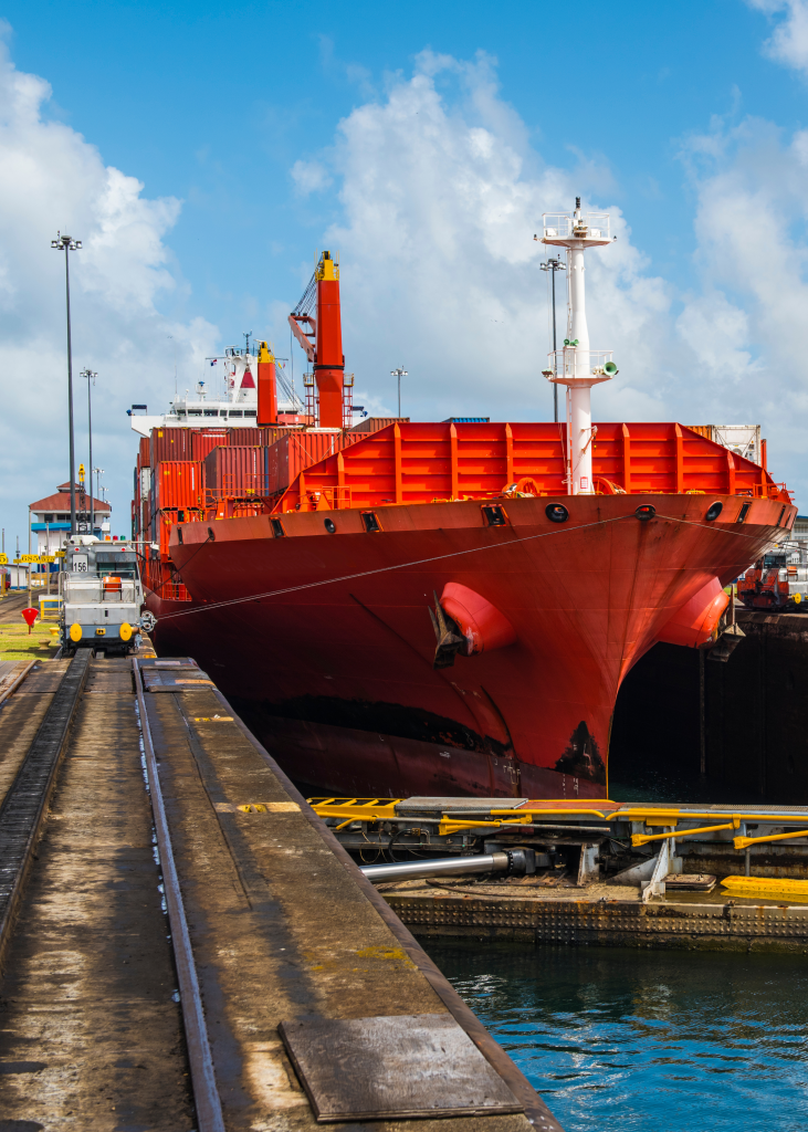 red tanker going through the panama canal with rail next to it