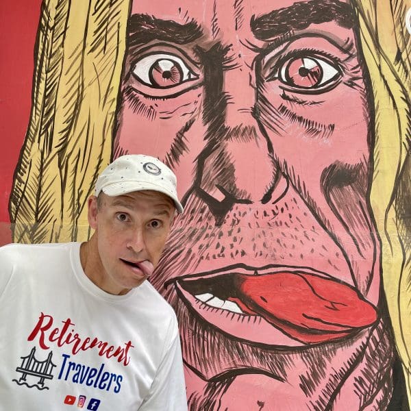 john sticking his tongue out with mural in background in medellin colombia