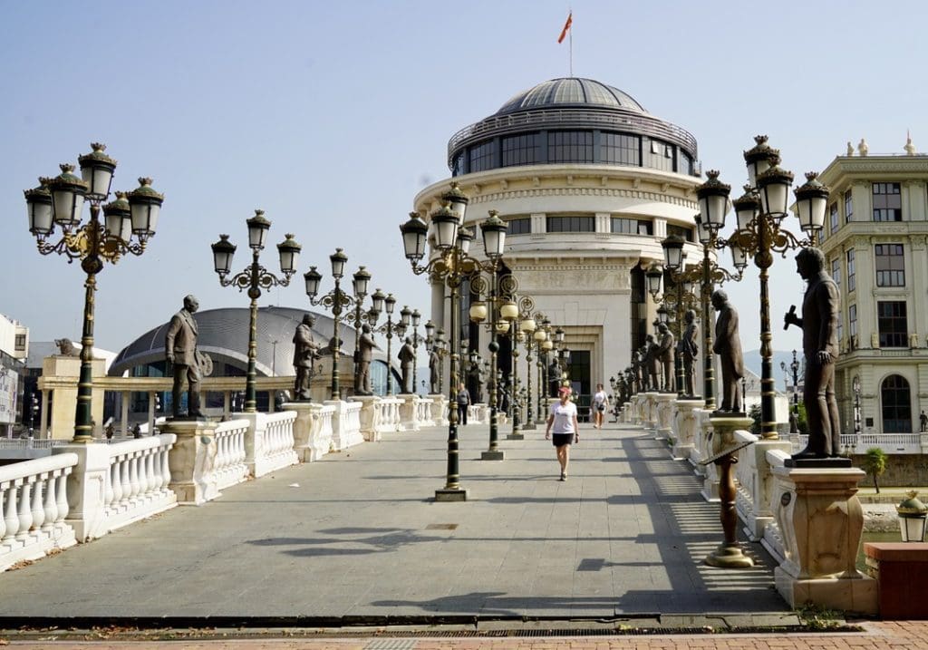 bev walking across the bridge surrounded by statues