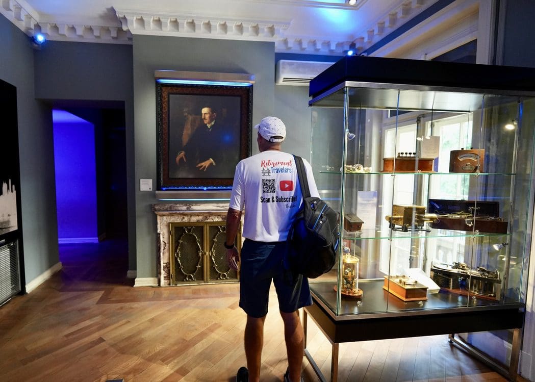john standing in front of portrait of tesla