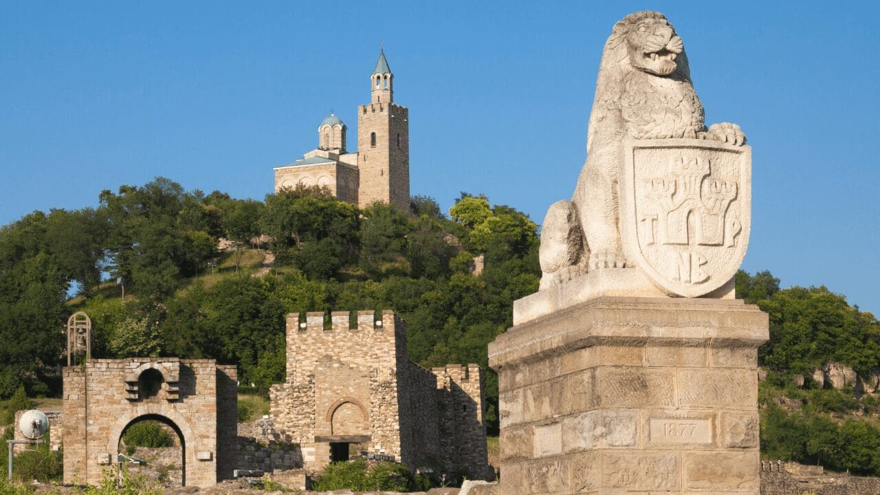 in the distance the fortress sits on a hill with lions near the foreground