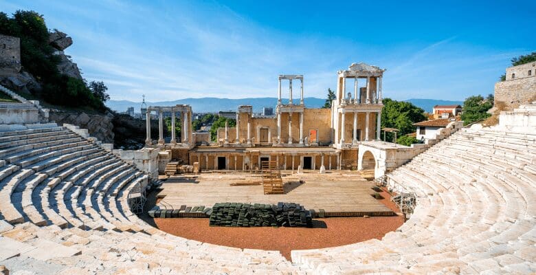 roman amphitheater with reddish marble seating and roman columns around stage