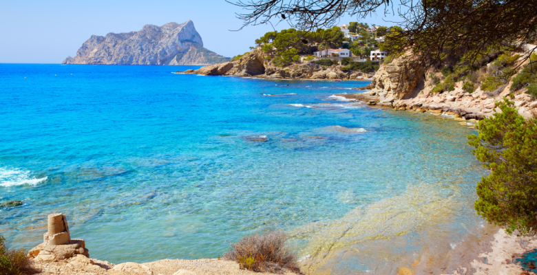 Cala Pinets Beach in Alicante, Spain with deep blue water and sandy beach.