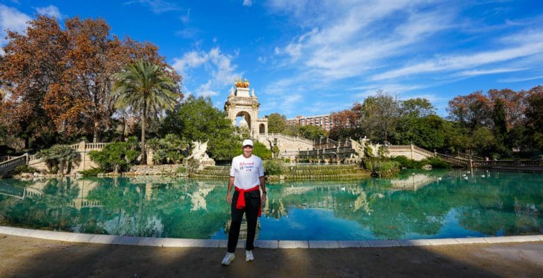Man standing in front of large pool with statues in a park in Barcelona, Spain