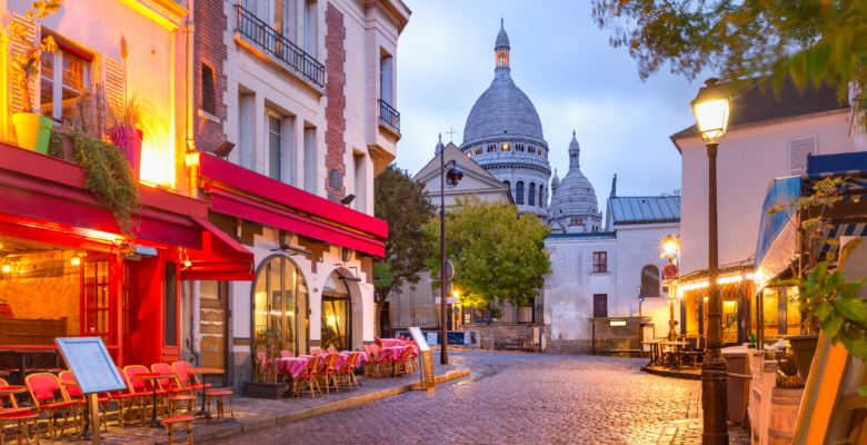 Cobblestone Street in Paris with streetlights, restaurants, and church in background