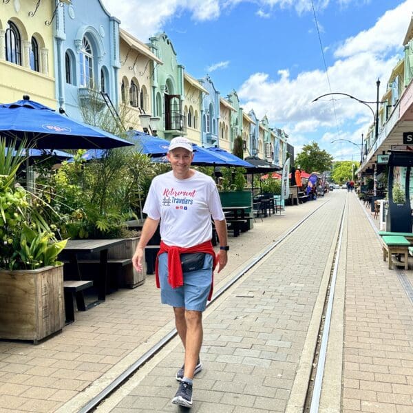 Man walking down a street used by trolleys with homes and restaurants lining the street in Christchurch, New Zealand