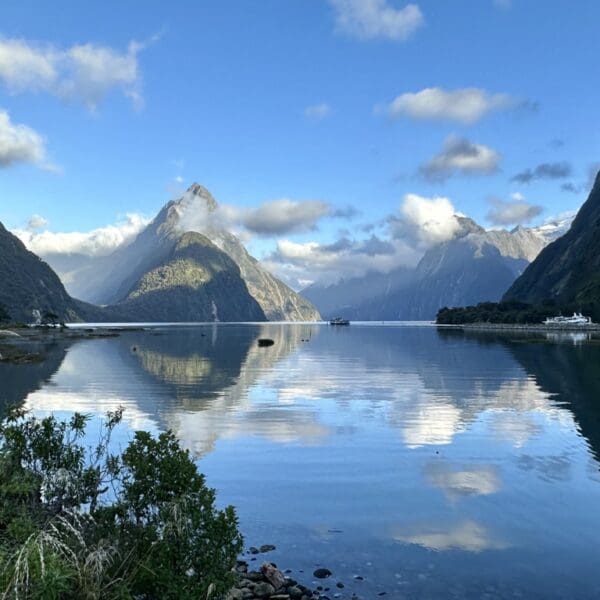 Beautiful still body of water surrounded by steep, large mountains reflecting in the water.
