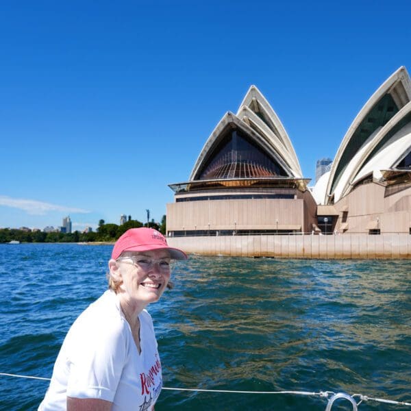 a woman on a boat with a view of the Sydney Opera House from the water