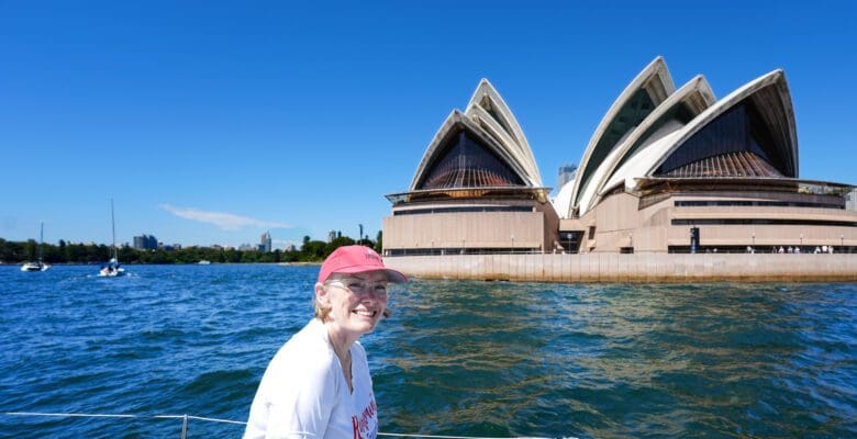 a woman on a boat with a view of the Sydney Opera House from the water