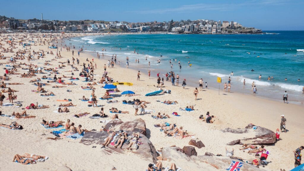 crowded beach area with shoreline and waves coming in