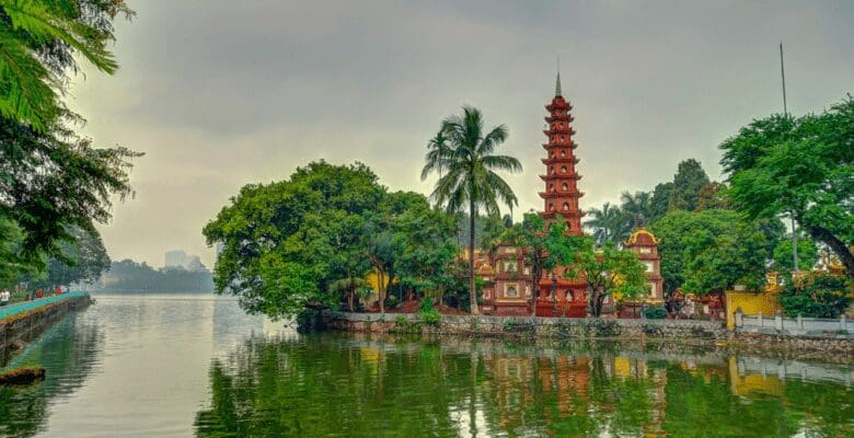 View of an ancient temple surrounded by tall lush green trees and water.