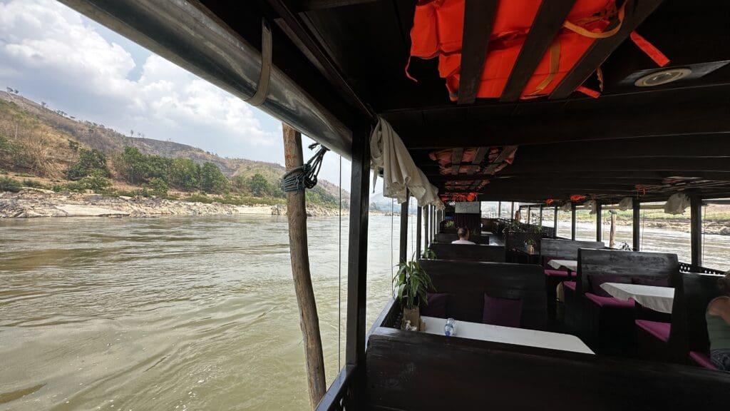 View of seating of a long boat with views of river and shore