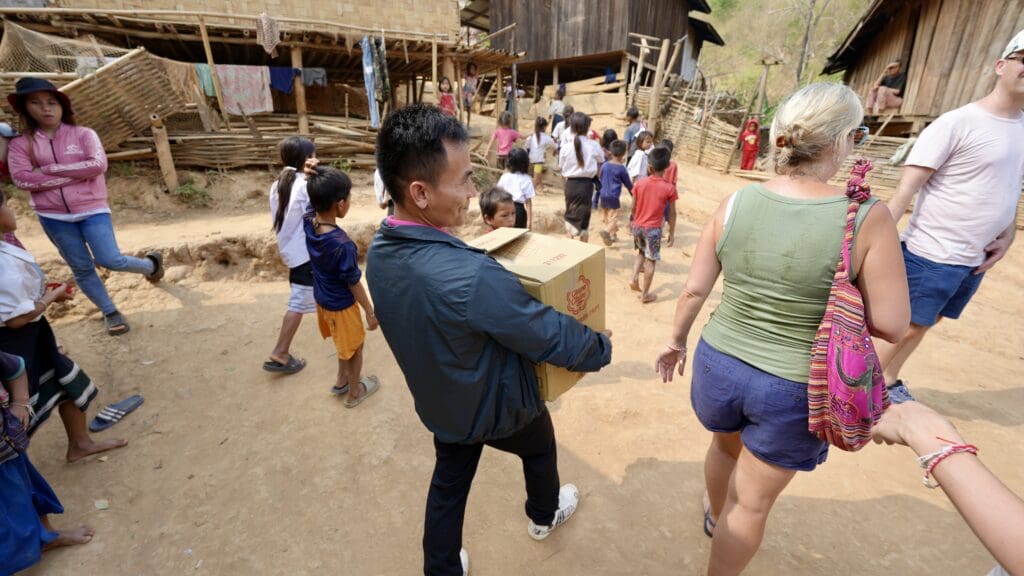 man carrying box and people walking in a dirt area