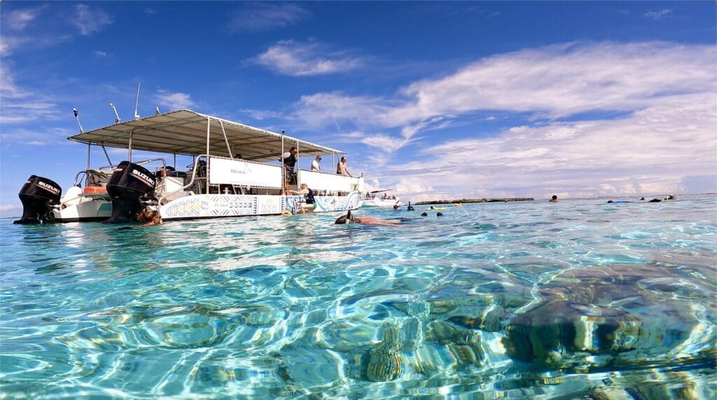 People snorkeling near a pontoon boat in Moorea