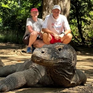 John and Bev retirement travelers kneeling behind a komodo dragon