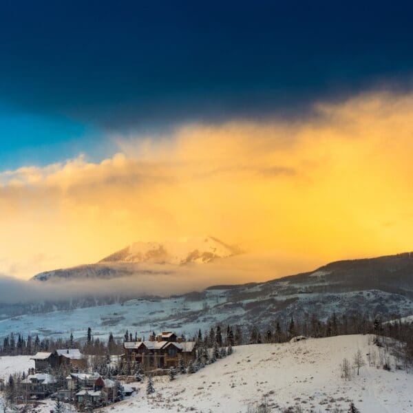 Mountain scene with snow, tress, clouds and a few hillside houses