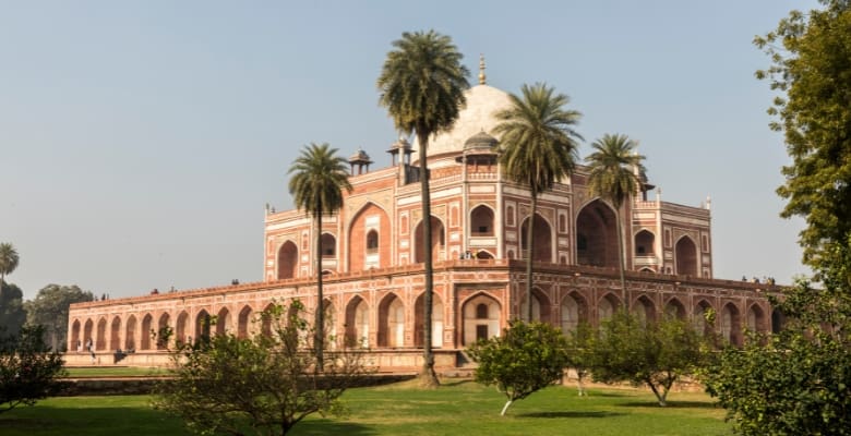 Magnificent bricked tomb with arched openings and surrounded by grass and palm trees