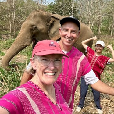 John and Bev retirement travelers with an elephant and another person in Thailand