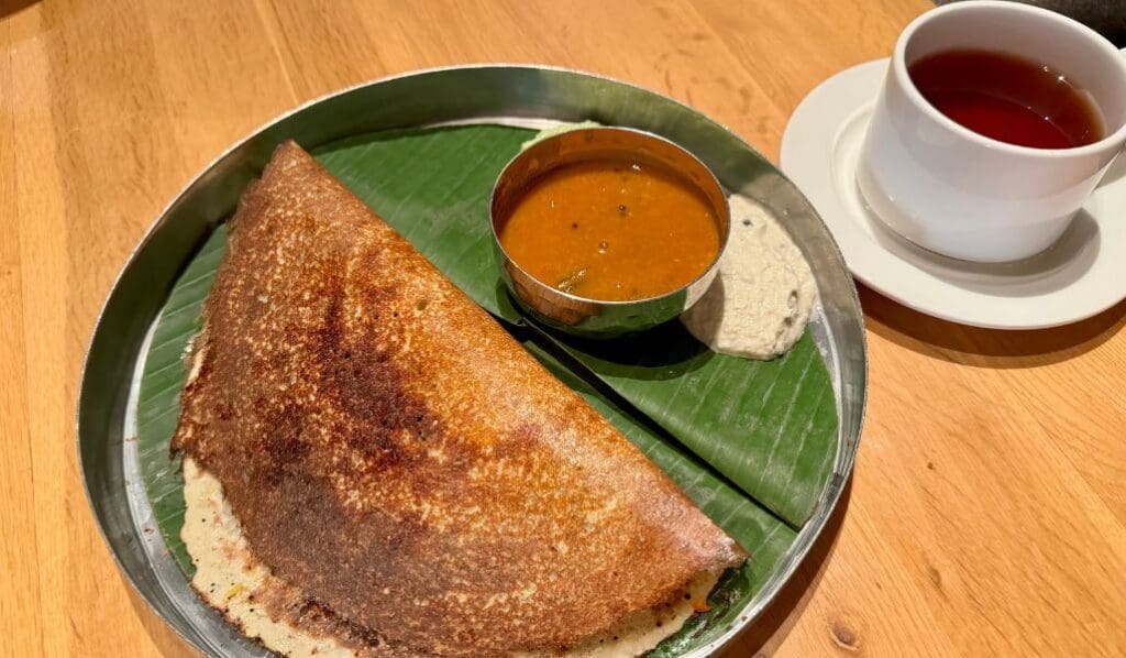 traditional indian food on a plate with cup of tea